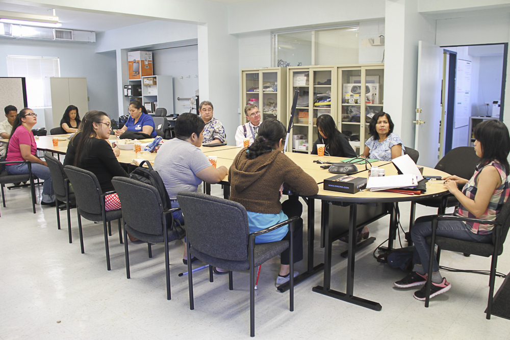 Group sitting around a table while watching the Orcam demonstration.